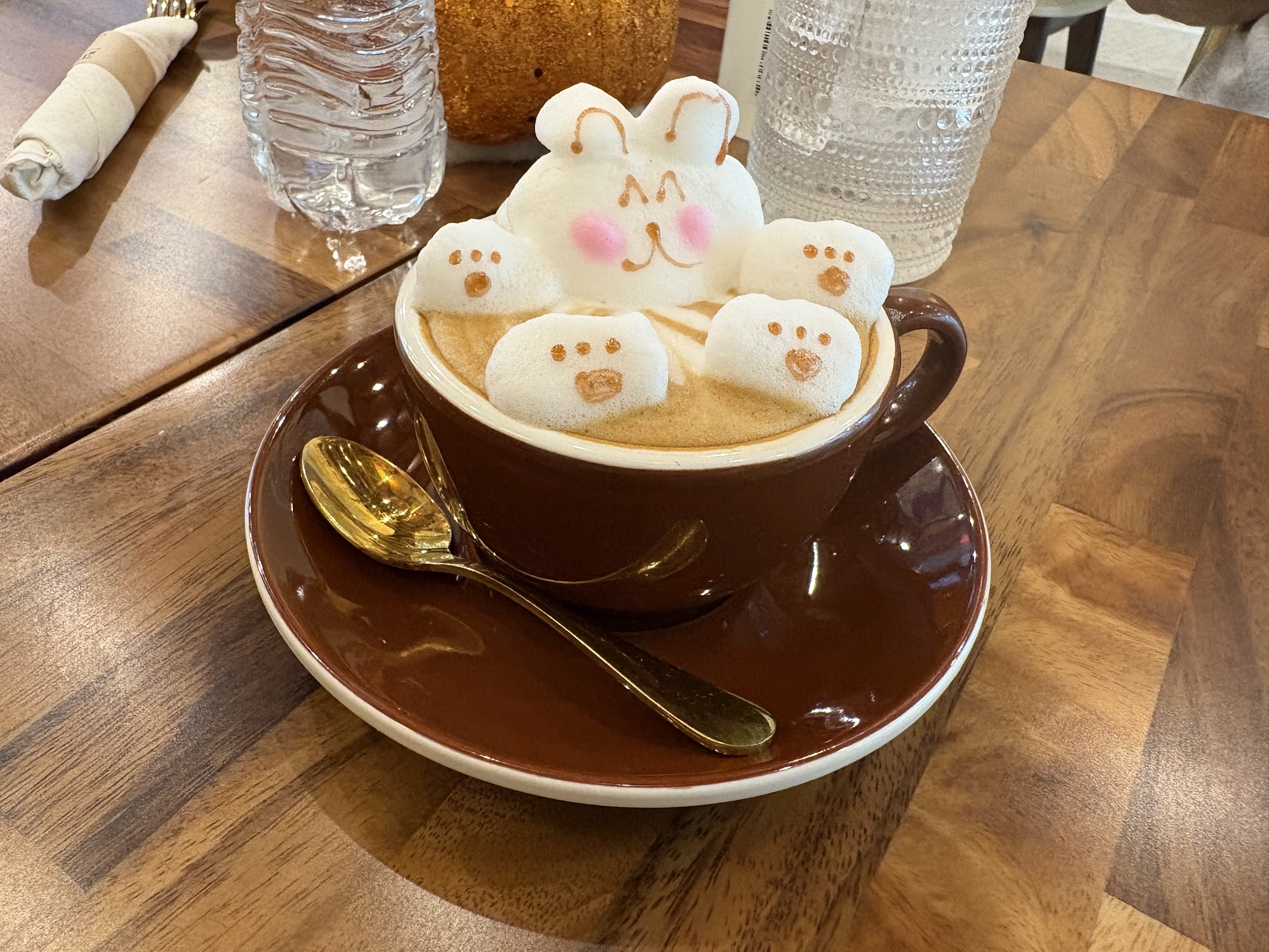 Dark coffee cup with a cat-shaped foam design on a wooden table